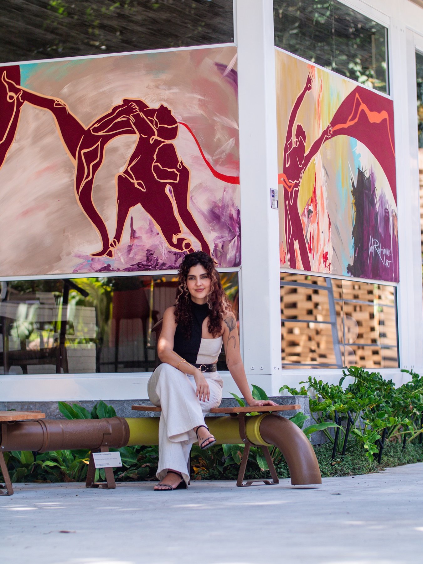 Gabi Rodrigues seated in front of the external panel she painted